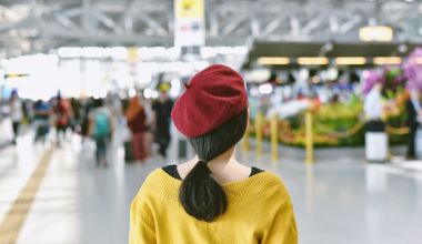 Asian woman standing in trade fair exhibition hall, Blurred background of large crowded people at big event with copyspace.