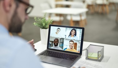 Modern laptop on the office table during the video conference. Man writing in the notebook