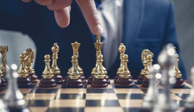 Businessman pointing his finger at a gold Chess King figure. Successful strategy, management, business planning and leadership concept. Toned retro effect