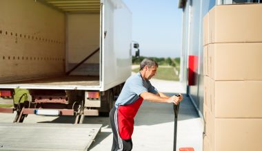 Logistics worker carrying delivered goods into warehouse